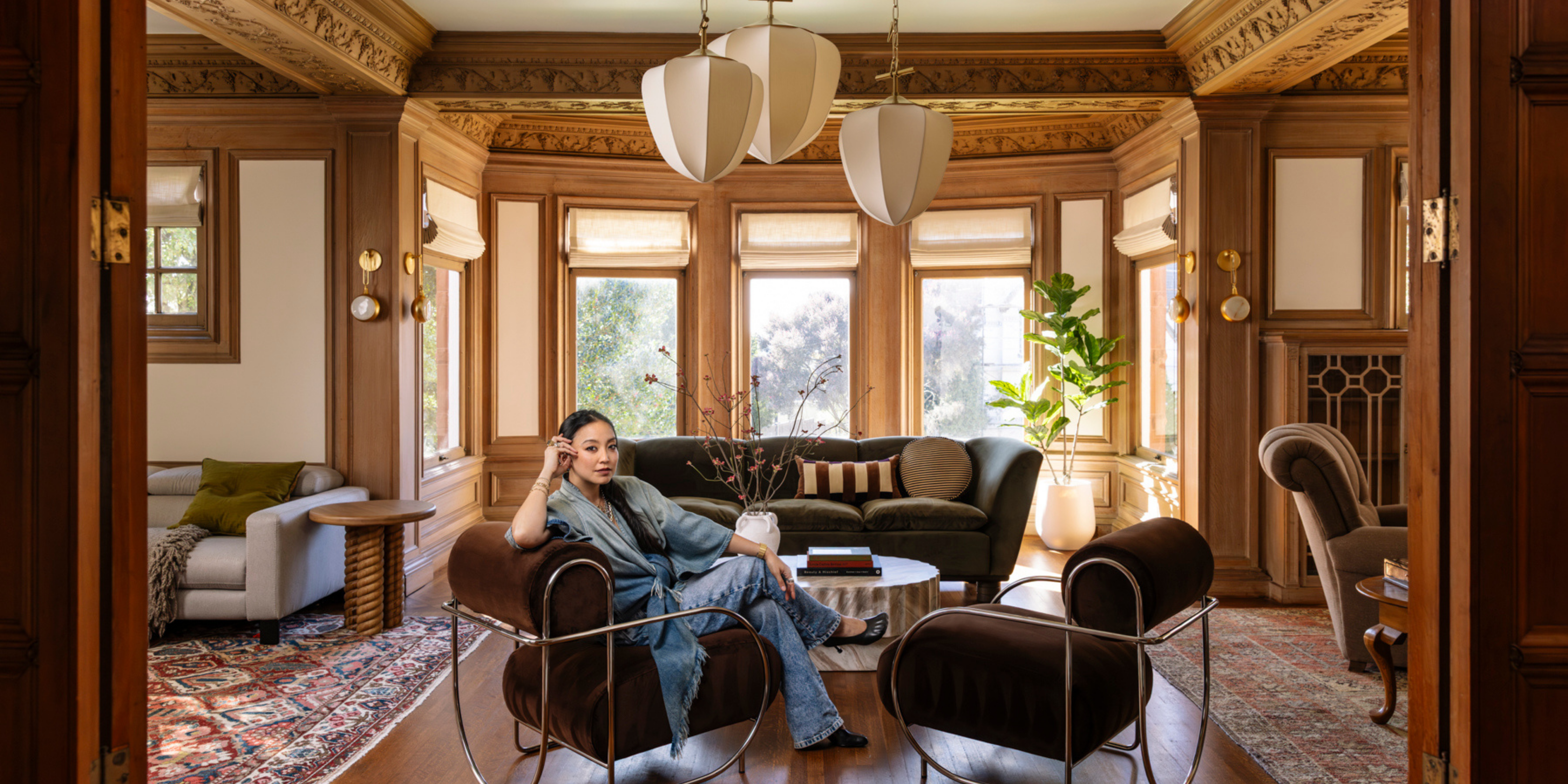 woman standing in a dining room underneath a large chandelier